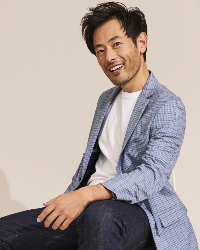 A man in a casual outfit, wearing a Tommy Hilfiger t-shirt with a crouching still, striking a pose for a photograph.